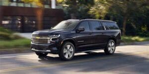 A black chevrolet suburban driving down the street.